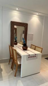 una mesa con sillas y un espejo en una habitación en Boulevard Riviera Flat, en Bertioga