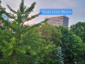 ein Zeichen, das ein Unilinkaminamineamin hinter Bäumen liest in der Unterkunft Gemütliches Privatzimmer an der Uniklinik Mainz. Sehr zentral in Mainz
