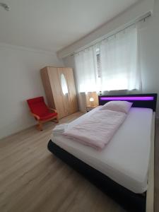 ein Schlafzimmer mit einem Bett und einem roten Stuhl in der Unterkunft Gemütliches Privatzimmer an der Uniklinik Mainz. Sehr zentral in Mainz