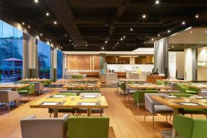 a restaurant with wooden tables and green chairs at Aloft Nanhai, Foshan in Nanhai