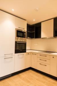 una cocina con armarios blancos y electrodomésticos negros en Chic Retreat - 1-Bedroom Haven en Accra