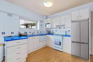 a kitchen with white cabinets and blue counter tops at Bridge View 2 Bed Apartment at Kirribilli in Sydney