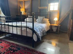 a bedroom with a black bed and a window at Alfie Acres - Secluded Cabin set in 5 Acres of Privacy, with Exclusive use of Swimming Pool and Hot Tub for up to 10 Guests in Downham