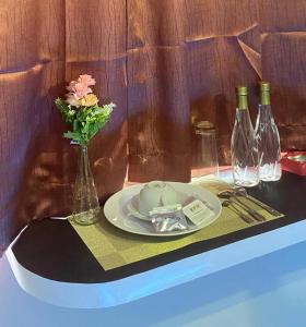 un tavolo con un piatto e un vaso di fiori e bottiglie di vino di Keypayroom a Kemirimuka Dua