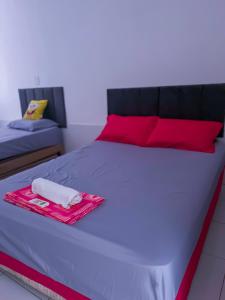a bed with red pillows and a towel on it at Localizada no centro de Juazeiro in Juazeiro