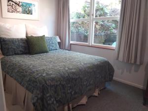 Bett in einem Zimmer mit 2 Fenstern in der Unterkunft Coromandel Eco Sanctuary in Coromandel Town