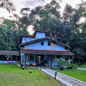 ein kleines blaues Haus auf einem Feld mit Bäumen in der Unterkunft Casa praia de camburi in São Sebastião