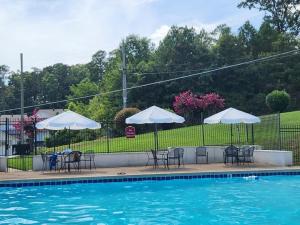 a pool with tables and chairs and umbrellas next to at LAKEFRONT 7 MIN to OAKLAWN & 10 MIN to DOWNTOWN STR License #A22-0004 in Hot Springs