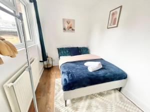 a bedroom with a bed with blue sheets and a window at 3 Bedrooms London Urban Escape in London