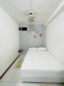 Cama blanca en habitación pequeña con techo en HOSTAL AMA, en Leticia