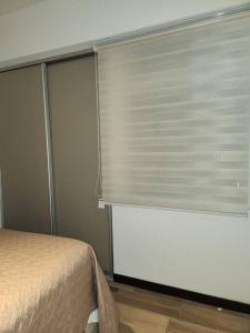 a bedroom with a bed and a window with blinds at Bonito Apartamento en zona exclusiva y tranquila in Quetzaltenango