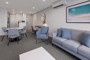 a living room with a couch and a table and chairs at Meriton Suites Broadbeach in Gold Coast