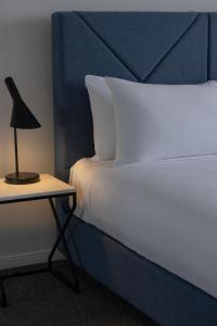 a bed with a side table with a lamp on it at Meriton Suites Broadbeach in Gold Coast