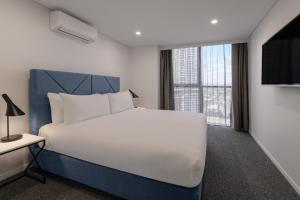 a bedroom with a white bed and a large window at Meriton Suites Broadbeach in Gold Coast