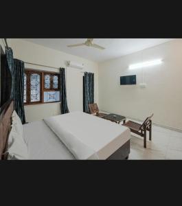 a bedroom with a large white bed and a chair at OYO Zora Luxury Rooms in Visakhapatnam