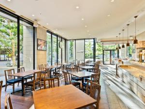 ein Restaurant mit Holztischen, Stühlen und Fenstern in der Unterkunft Mitsui Garden Hotel Kashiwa-No-Ha - Chiba in Kashiwa