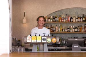 a man standing behind a bar with a box of alcohol at Wake Up! Byron Bay in Byron Bay