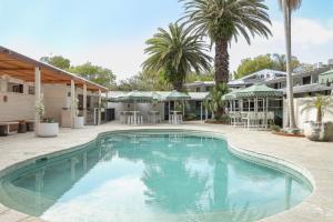 a swimming pool in a courtyard with palm trees at Wake Up! Byron Bay in Byron Bay