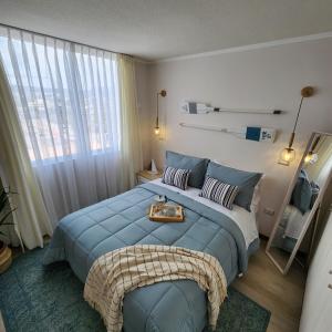 um quarto com uma cama azul com uma bandeja em Depto cercano a playa El Faro La Serena em La Serena