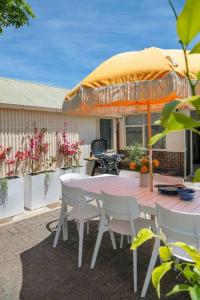 un tavolo e sedie con un ombrellone in un patio di Boutique by the Bay - Beach Wifi Nespresso a Glenelg