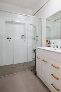 a white bathroom with a shower and a sink at Boutique by the Bay - Beach Wifi Nespresso in Glenelg