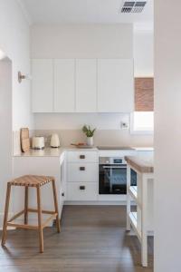 una cucina con armadi bianchi e sgabello di Boutique by the Bay - Beach Wifi Nespresso a Glenelg Altre 17 foto