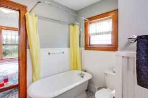 ein Bad mit einer Badewanne, einem WC und einem Fenster in der Unterkunft Artist’s Vintage Home 5 mins from ND Campus in South Bend