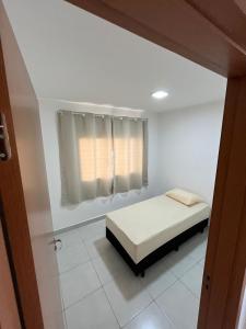 a small bedroom with a bed and a window at Apartamento 2 quartos in Goiânia
