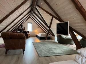 a attic room with a tv and a couch and a chair at Apartment downtown - Great View! in Klaksvík