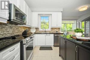 a kitchen with white cabinets and black counter tops at Luxury - Beautiful Place for Group Gatherings in Vaughan