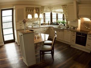 a kitchen with white cabinets and a table and chairs at Villa Victoria in Rydzewo