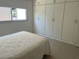 ein weißes Schlafzimmer mit einem Bett und einem Fenster in der Unterkunft Departamento de dos dormitorios y terraza con asador in Yerba Buena