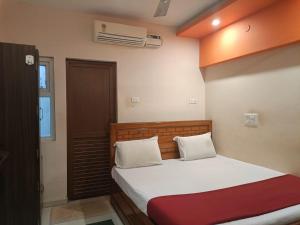 1 dormitorio con 1 cama con sábanas blancas y manta roja en Hotel Duwaraka, en Rameswaram