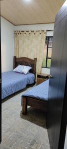 a bedroom with two beds and a door with a door at Posada Campestre Macadamia in Paipa
