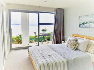 a bedroom with a large bed and a large window at Once Upon a Tide in Auckland