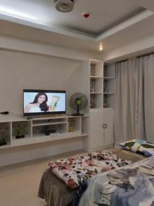 Pasay OnePalm Tree Villas 7N C3 في مانيلا: غرفة نوم بسرير وتلفزيون بشاشة مسطحة