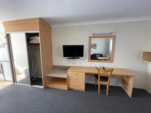 a room with a desk with a television and a mirror at George Bass Motor Inn in Nowra