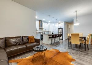 a living room with a couch and a table and a kitchen at Stylish/4Bedroom/FreeParking/IndoorFirePlace in Calgary