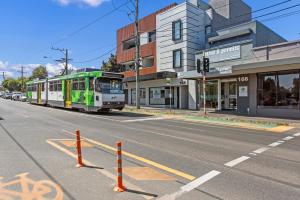 a bus is driving down a city street at Queensview168 Apartments Moonee Ponds in Melbourne