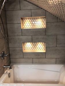 a bathroom with a bath tub and two lights at Escape, mins from Airport, EY Centre, Casino, Golf in Ottawa