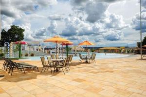 カルダス・ノバスにあるLacqua diRoma - Serviço de Hotelariaのパティオ(パラソル付きの椅子とテーブル、プール付)