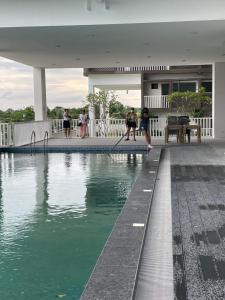 a swimming pool with people sitting on the deck of a house at WV Tower 1 Studio in Iloilo City