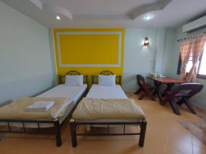 2 camas en una habitación con mesa y escritorio en Mongnon Hotel โรงแรมมองนอน อุดรธานี, en Udon Thani