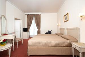 - une chambre avec un lit, un bureau et une fenêtre dans l'établissement Grand Hôtel Moderne, à Lourdes