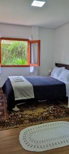 a bedroom with a bed and a window and a rug at Recanto Ursa Maior in Monte Verde
