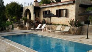 una piscina con sedie e una casa di Garden of Eden Villa a Paphos