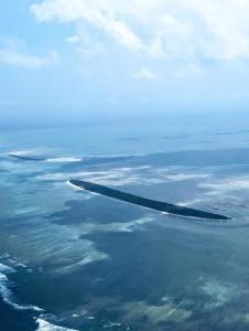 a wing of an airplane flying over the ocean at Résidence Véronia in Rodrigues Island