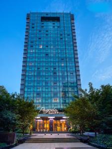 a tall glass building with a store in front of it at Hangzhou West Lake Wulin Pagoda Junting Design Hotel in Hangzhou