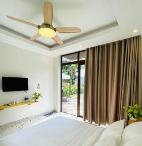 um quarto com uma ventoinha de tecto e uma televisão em Sol Inn - Moc Chau em Mộc Châu