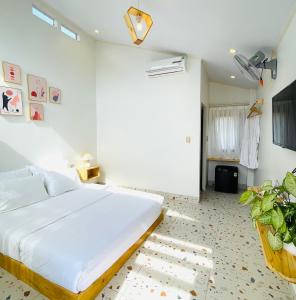 biała sypialnia z łóżkiem i rośliną w obiekcie Sol Inn - Moc Chau w mieście Mộc Châu